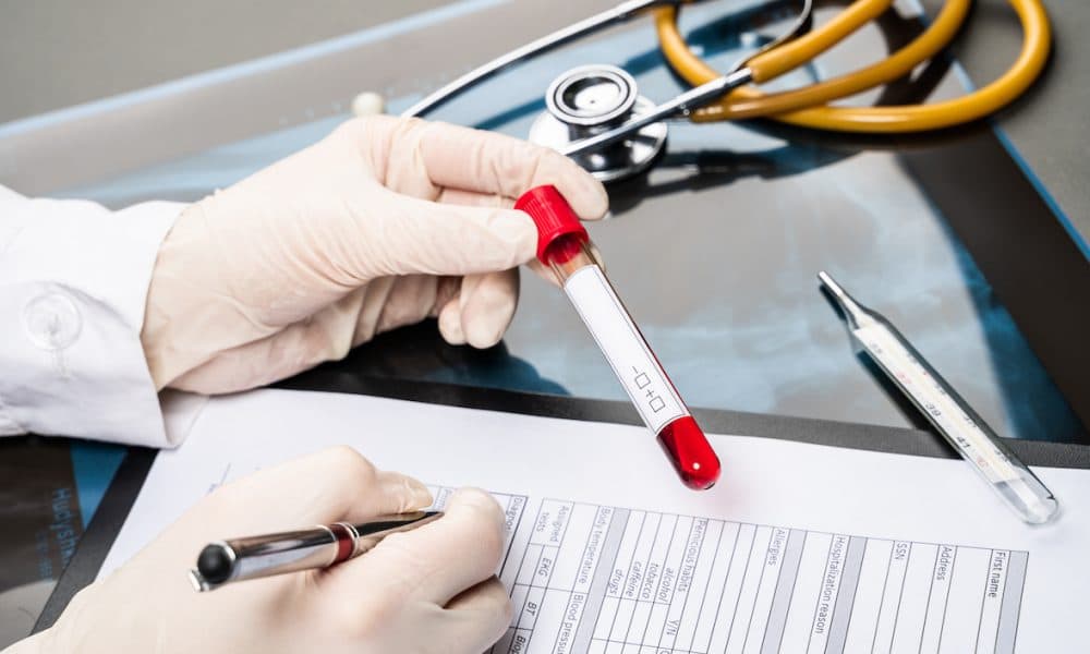 medical doctor ‘s hand holding blood sample and making notes writing patients data on prescription Wellbeing Software expands to support diagnostic services