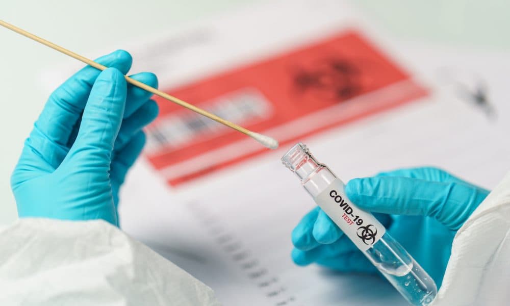 Hand holding COVID-19 swab collection kit, specimen sample testing process. Crisis looms over dangerously high level of used Covid tests