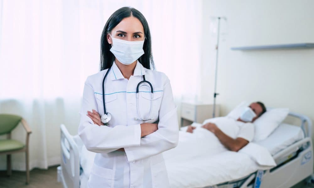 A confident doctor woman in a safety medical mask is examining a mature patient in the mask while he lying in the ward. Smart inspections app spreads global reach