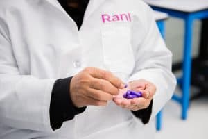 A person in a Rani Therapeutics lab coat counts purple capsules