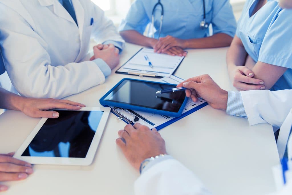 A group of doctors sitting around a table discussing an online platform