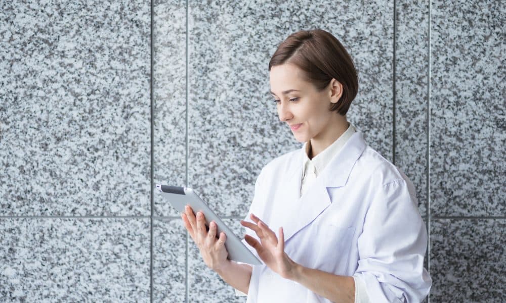 タブレットPCを持つ白衣の若い女性 Clinical research: A digital age video revolution