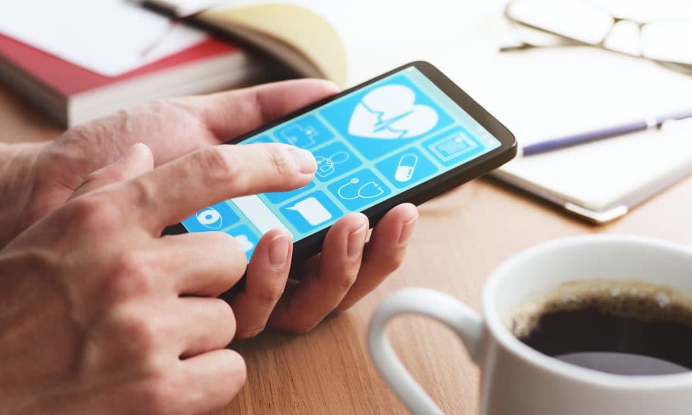 Online healthcare app on smartphone screen. Closeup of male hand App slashes emergency hospital admissions from care homes