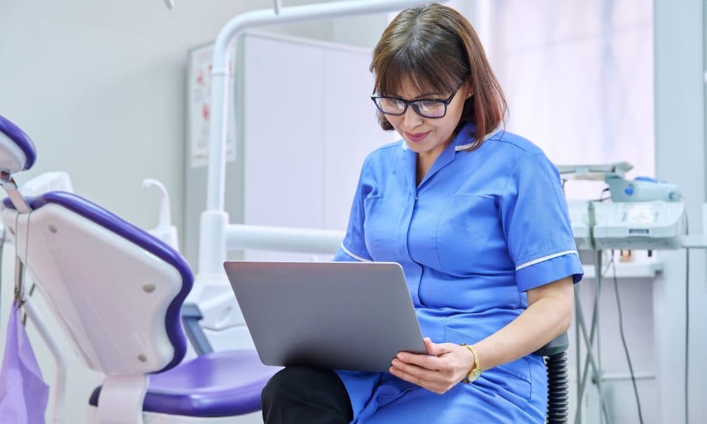Doctor nurse dentist sitting in the office using a laptop. NHS Scotland’s Right Decision Service built on Tactuum technology