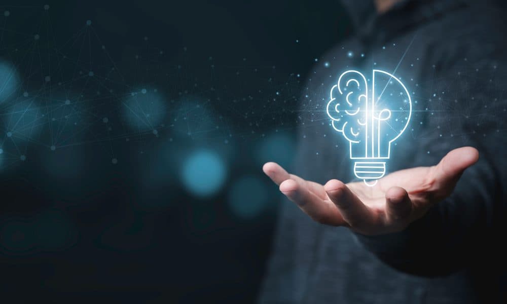 Businessman holding half of virtual lightbulb and brain on blue Trends in patents and innovation against cancer