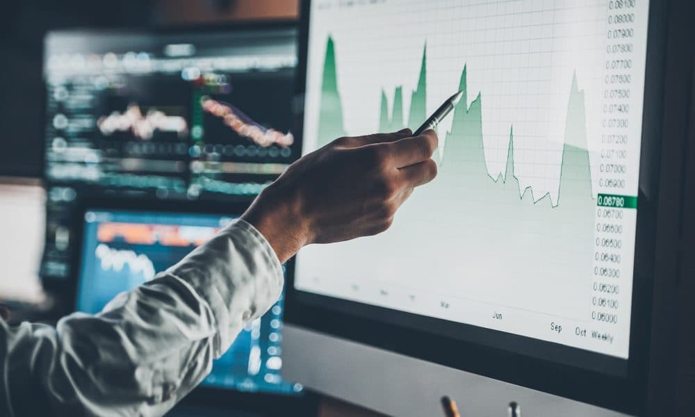 Analyzing data. Close-up of young businessman pointing on the data presented in the chart with pen while working in creative office Why standards are key to building trust in AI
