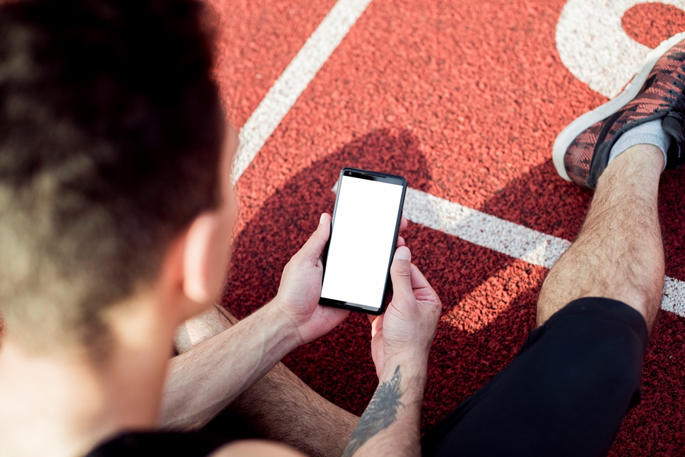 overhead-view-male-athlete-sitting-race-track-using-mobile-phone Gamification in Digital Health Apps: What Can Be Learned from Gaming Platforms