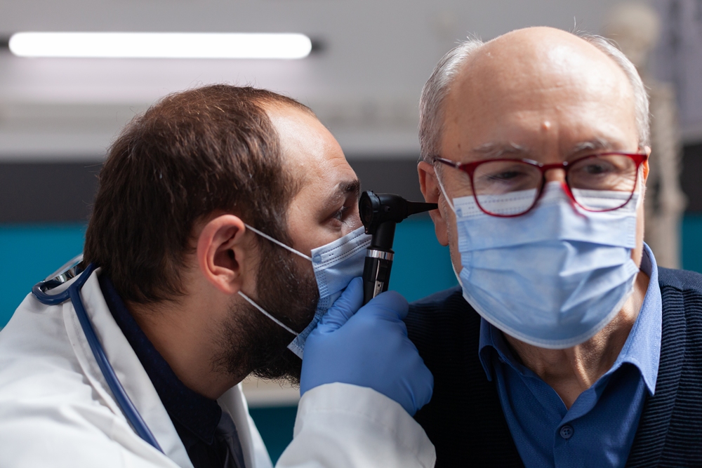 Medic using otoscope to do ear checkup on senior man How AI is transforming ENT and rhinoplasty practice