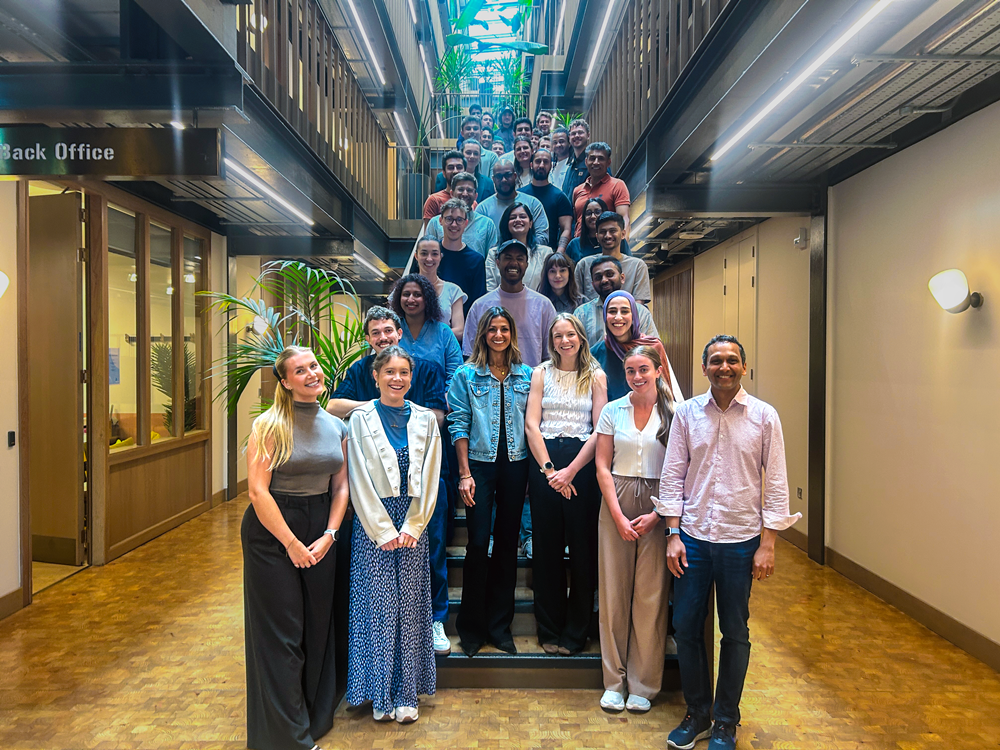 Large diverse group of coworkers posing on a stairwell in a modern office hallway.